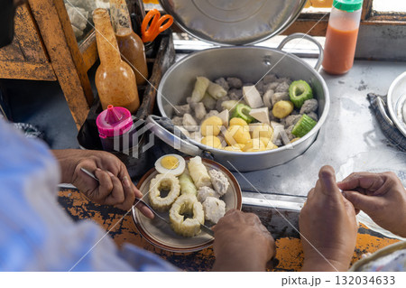 Traditional Indonesian street food vendor preparing Siomay, a popular steamed fish dumpling dish, for a customer. Traditional Indonesian street food vendor preparing Siomay, a popular steamed fish dumpling dish, for a customer. 132034633