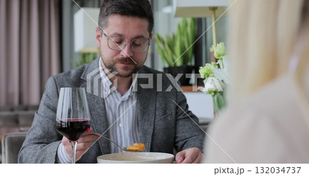 Couple having a dinner at a restaurant. People enjoying their date, drinking wine, eating and chatting. Couple having a dinner at a restaurant. People enjoying their date, drinking wine, eating and chatting. 132034737