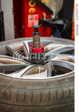 Car wheel positioned on a tire changing machine before removing the tire from the rim. Seasonal tire replacement process at an auto service during winter preparation. 132034758
