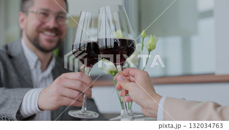 Couple clinking glasses of wine in restaurant. Two people celebrating anniversary together in cafe close-up. 132034763