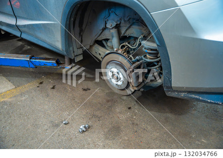 Exposed car wheel hub and brake disc after tire removal during seasonal maintenance. Essential stage of winter tire change for road safety and technical inspection. 132034766