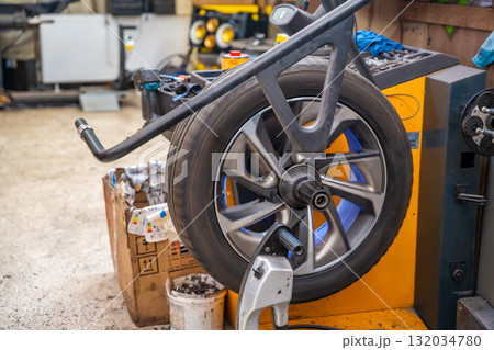 Car wheel rotating on a balancing machine during seasonal tire service at an auto workshop. Essential step to ensure smooth driving and tire longevity before winter installation. 132034780