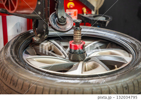 Tire changing machine removing the rubber tire from the rim using a rotating metal arm. Essential step in seasonal wheel replacement at a professional auto workshop. Tire changing machine removing the rubber tire from the rim using a rotating metal arm. Essential step in seasonal wheel replacement at a professional auto workshop. 132034795