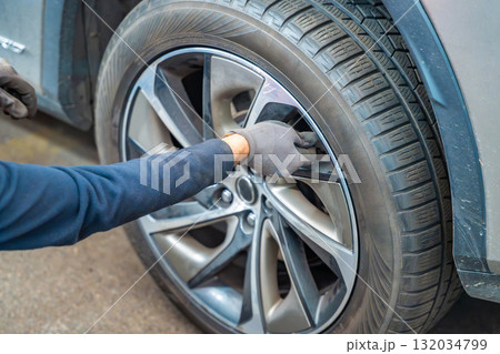 Mechanic closing tire valve after checking pressure during seasonal tire change. Essential step of car maintenance before winter in Czech Republic. Mechanic closing tire valve after checking pressure during seasonal tire change. Essential step of car maintenance before winter in Czech Republic. 132034799