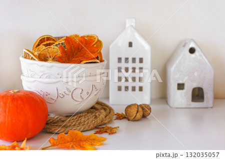 Autumn decoration with dried oranges, leaves, orange pumpkin in kitchen setting on white background 132035057