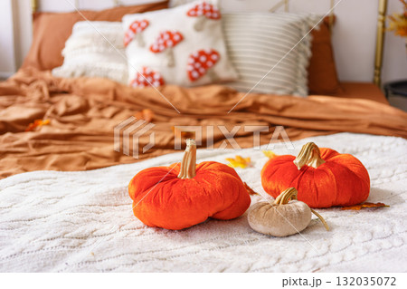 Cozy autumn bedroom decor with orange plush pumpkin pillows on blanket in bedroom, interior decor 132035072