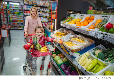 Happy mother and daughter shopping for fresh fruit in supermarket 132035489
