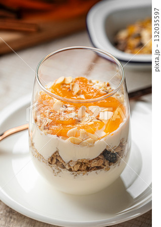 Yogurt dessert with granola and apricots in glass 132035597