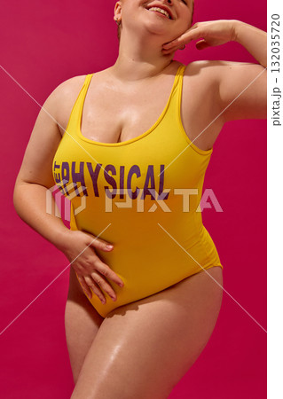 Smiling plus-size woman in yellow swimsuit posing confidently in bright fashion editorial style Smiling plus-size woman in yellow swimsuit posing confidently in bright fashion editorial style 132035720
