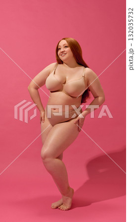 Confident woman posing in nude lingerie expressing joy and self-acceptance 132035732