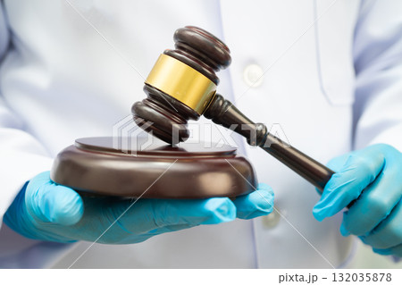 Asian doctor holding court hammer for and crime law justice, forensic medicine. Asian doctor holding court hammer for and crime law justice, forensic medicine. 132035878