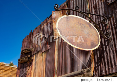 Blank metal antique shop sign. Oval shape vintage signboard with empty space hanging on wrought iron 132036211