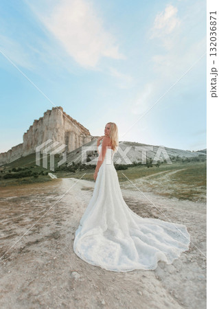 a woman in a white dress, a bride on a mountain with a blue sky. Beautiful nature, freedom, enjoyment of life. High quality photo 132036871