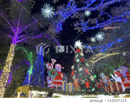 Outdoor holiday display featuring Santa Claus, green trees, and thousands of colorful lights. The night scene glows with festive cheer and sparkling Christmas spirit. 132037125