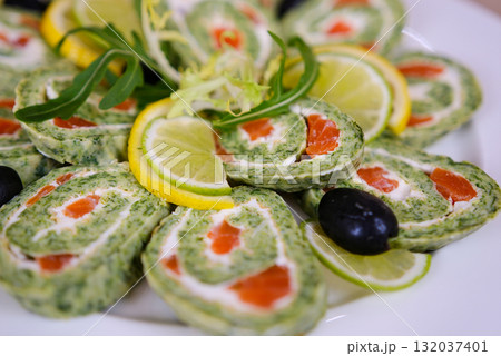 Spinach roulade stuffed with cream cheese and smoked salmon sliced on a white background, top view 132037401