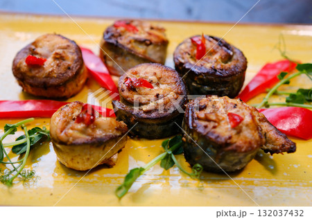 mackerel rolls healthy baked fillet of mackerel in rolls slices on white dish on cutting board with fork and knife, spices and plate with cherry tomatoes on background, close-up 132037432