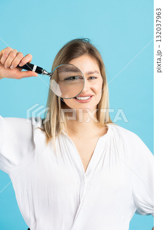 Studio portrait of woman with magnifying glass Studio portrait of woman with magnifying glass 132037963