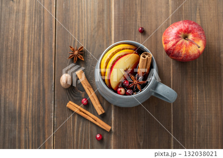 A cup of red mulled wine with spices, orange, apple slices and cranberry on a wooden background A cup of red mulled wine with spices, orange, apple slices and cranberry on a wooden background 132038021