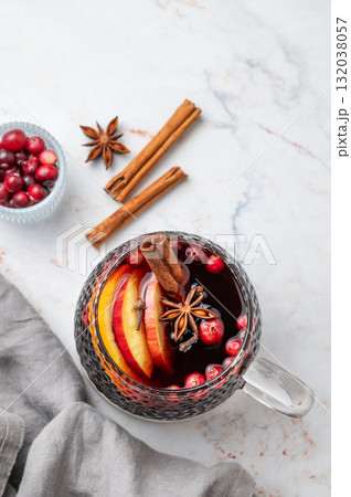 A cup of hot mulled wine with spices, orange and apple slices, cinnamon on a marble background 132038057