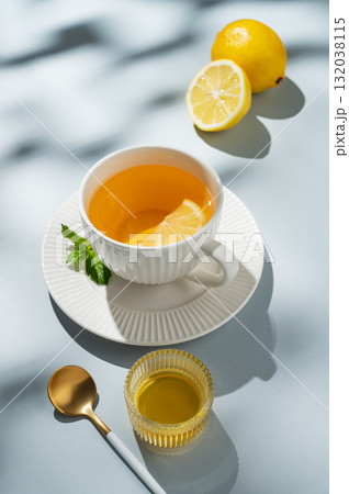 Hot tea with lemon, ginger, honey, and mint in a cup on a blue background with citrus fruits 132038115