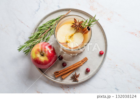 Hot apple cider with cinnamon, anise, and rosemary in glass on a marble background with cranberry Hot apple cider with cinnamon, anise, and rosemary in glass on a marble background with cranberry 132038124