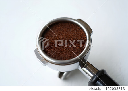 Freshly ground coffee packed into professional espresso machine portafilter, ready for brewing, isolated on white background 132038218