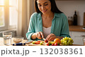 Hispanic woman managing diabetes by preparing a healthy meal. Slicing fresh fruit with a blood glucose meter on the counter. Healthy lifestyle and nutrition concept Hispanic woman managing diabetes by preparing a healthy meal. Slicing fresh fruit with a blood glucose meter on the counter. Healthy lifestyle and nutrition concept 132038361