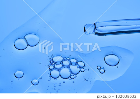 The texture of the facial serum on a blue background with pipettes. 132038632