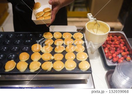 Baker preparing mini pancakes with strawberries in a busy kitchen during a lively brunch service Baker preparing mini pancakes with strawberries in a busy kitchen during a lively brunch service 132039068