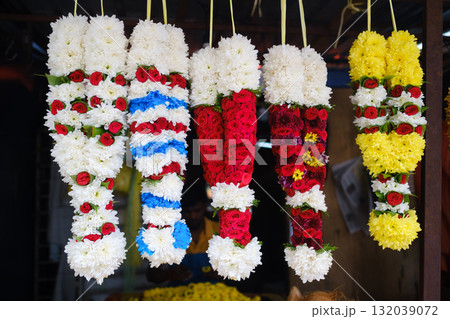 Colorful floral garlands hanging at a vibrant market stall showcasing traditional Indian floral arrangements for special occasions Colorful floral garlands hanging at a vibrant market stall showcasing traditional Indian floral arrangements for special occasions 132039072