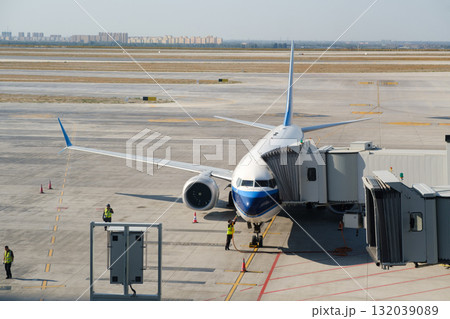 Plane docking at the airport gate with crew preparing for passenger boarding on a sunny afternoon Plane docking at the airport gate with crew preparing for passenger boarding on a sunny afternoon 132039089