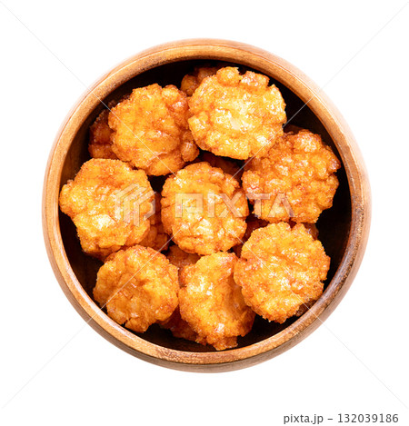 Thai chili rice crackers in a wooden bowl. Hot, sweet and spicy crispies, a snack made of rice, seasoned with chili powder and flavored with soy sauce. Close-up, from above, isolated over white. Photo 132039186