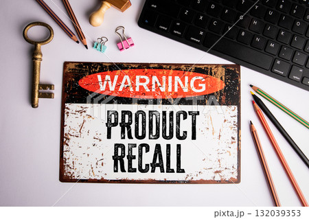 Warning product recall concept with vintage sign on desk surrounded by office supplies and keyboard 132039353