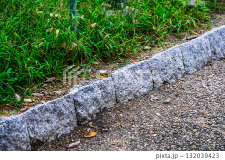 縁石と草むらの境界｜自然と都市のコントラストを写した舗装路 132039423