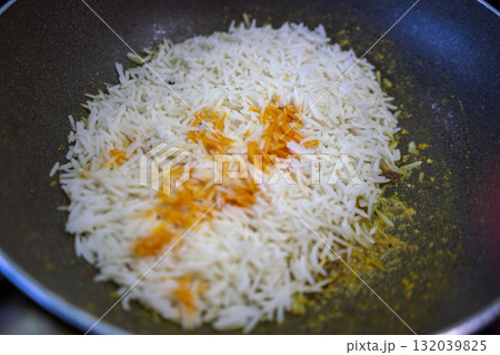 Chef preparing indian rice with saffron in a frying pan Chef preparing indian rice with saffron in a frying pan 132039825