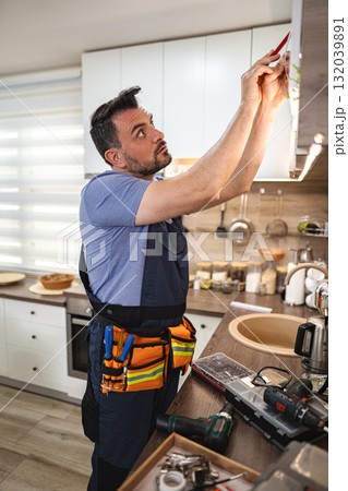 Handyman working on a kitchen furniture installation 132039891