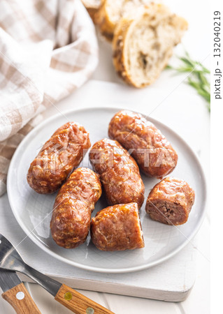 Photo of roasted italian sausage salsiccia on plate on white table. 132040219