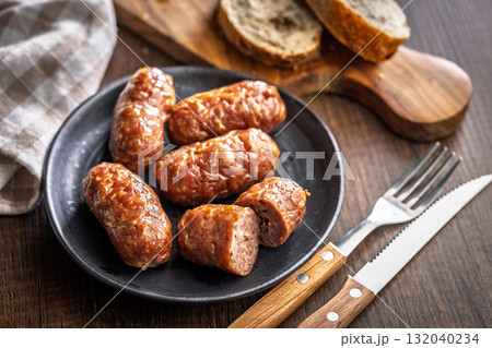 Photo of roasted italian sausage salsiccia on plate on wooden table. Photo of roasted italian sausage salsiccia on plate on wooden table. 132040234