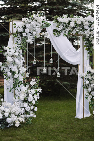 Wedding arch with white flowers and fabric in outdoor garden setting Wedding arch with white flowers and fabric in outdoor garden setting 132040424