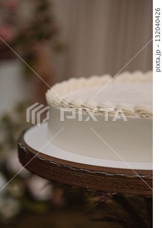 Close-up of white frosted cake on decorative stand with blurred background Close-up of white frosted cake on decorative stand with blurred background 132040426