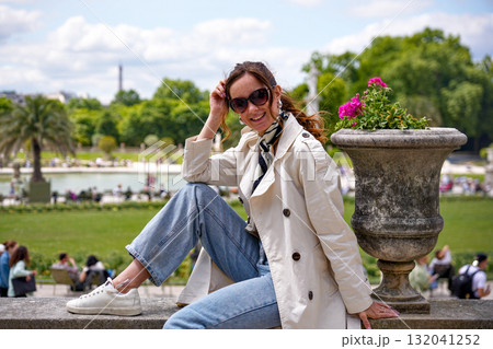 Smiling woman sitting by fountain in Luxembourg Gardens Paris 132041252