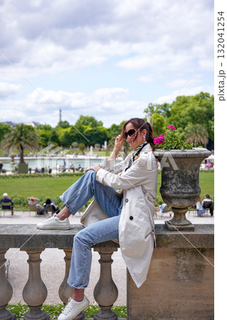 Smiling woman sitting by balustrade in Luxembourg Gardens Paris Smiling woman sitting by balustrade in Luxembourg Gardens Paris 132041254