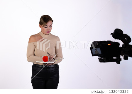A journalist is being filmed while preparing her notes for a report A journalist is being filmed while preparing her notes for a report 132043325