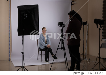 A photojournalist is capturing a portrait of a subject in a studio,  132043343