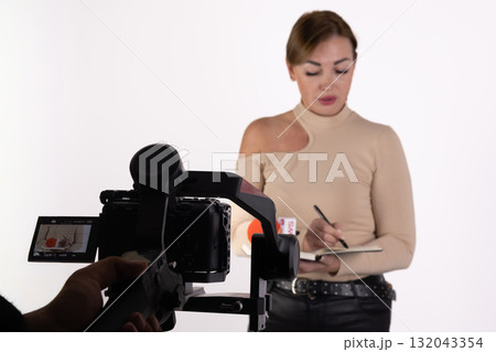 A journalist takes notes while being filmed for a news report 132043354