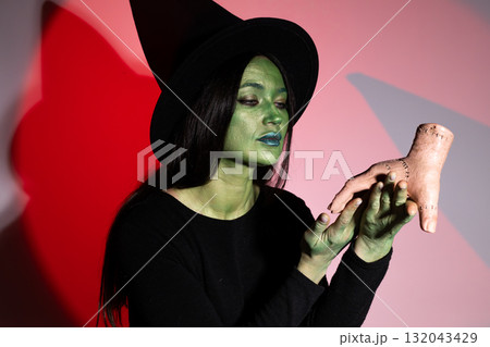 The witch is examining a dismembered hand as part of a Halloween ritual. 132043429