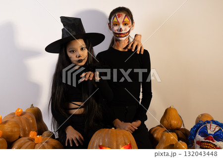 Two people in Halloween costumes are posing with pumpkins and jack-o'-lanterns Two people in Halloween costumes are posing with pumpkins and jack-o'-lanterns 132043448