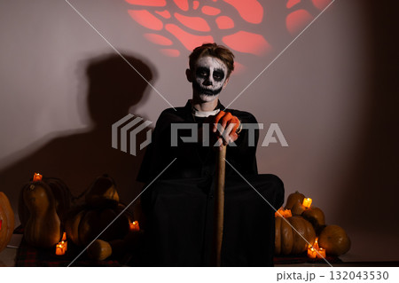 A person in Halloween makeup and costume is holding a staff while. 132043530
