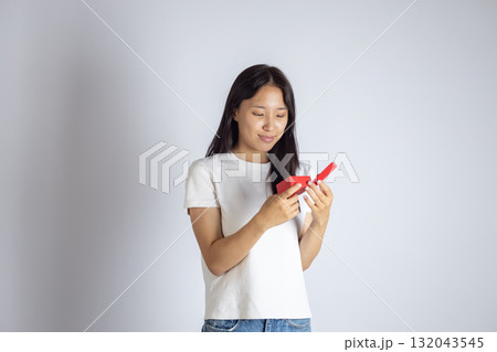 The model is holding a red object and looking down at it 132043545