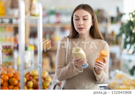Young woman chooses mustard or mayonnaise sauces Young woman chooses mustard or mayonnaise sauces 132043906